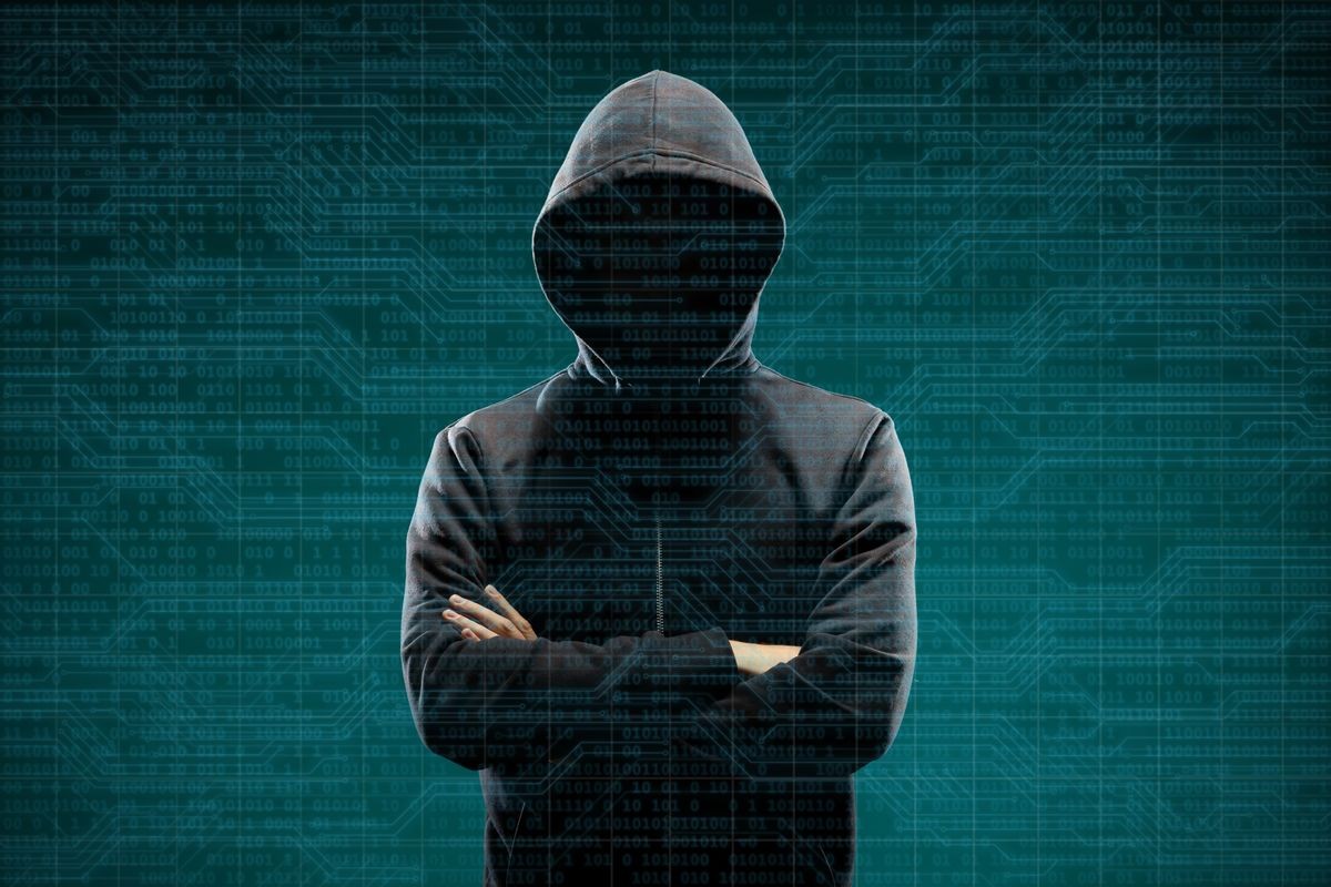 Anonymous computer hacker over abstract digital background. Obscured dark face in mask and hood. Data thief, internet attack, darknet fraud, dangerous viruses and cyber security.